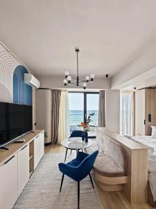 a bedroom with a bed and a table with a blue chair at Tomis Villa Grand Resort in Mamaia Sat/Năvodari