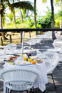 a table with white chairs and food on it at Hôtel des Roches Kourou in Kourou