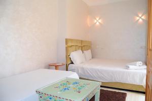 a room with two beds and a table in it at Riad Dar Lokman in Marrakesh