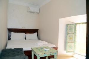 a small bedroom with a bed and a table at Riad Dar Lokman in Marrakesh