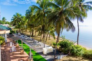 a row of chairs and palm trees on a beach at Hôtel des Roches Kourou in Kourou
