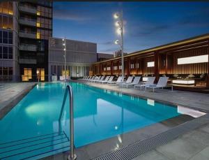 a large swimming pool with white chairs in a building at Central City Suites with Free Parking in Toronto