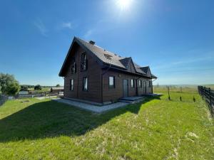 a house on a green field with a fence at Brajnickie Zacisze in Brajniki