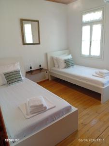 two beds in a white room with two windows at Avli in Samothraki