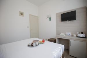 a white room with a bed and a tv on the wall at B&B Ortensia in Forte dei Marmi