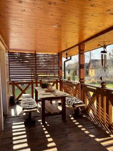a porch of a wooden cabin with benches and a table at Uroczysko Lady in Lady