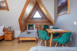 a bedroom with a bed and a table with green chairs at U Studniara in Murzasichle