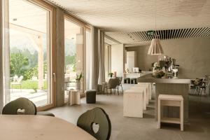 a living room with tables and chairs and a kitchen at Hotel Tulie in Most na Soči
