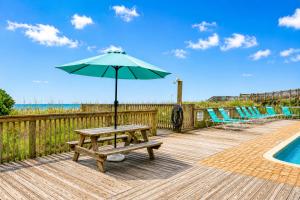 a picnic table with an umbrella next to a pool at Ocean Forest Colony in Myrtle Beach