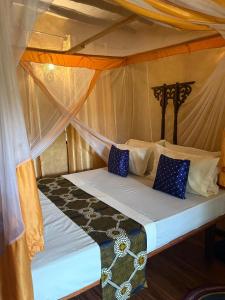 a bed in a tent with blue pillows on it at Serene Apartments in Kinyasini