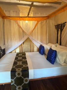 a bed in a tent with two blue pillows on it at Serene Apartments in Kinyasini