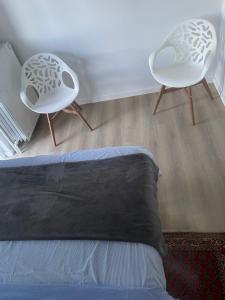 a bedroom with two white chairs and a bed at Campe Good in Waterloo
