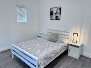 a white bedroom with a white bed and a night stand at Watford Junction Stay in Watford