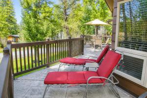 a porch with red chairs and an umbrella at Falcon Cabin in Fairmont Hot Springs