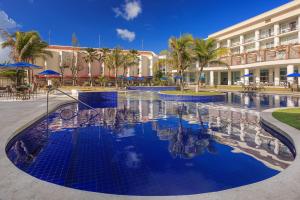 a pool at a resort with palm trees and a building at Marupiara Resort by Wish in Porto De Galinhas