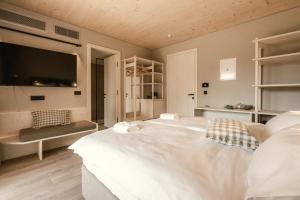 a bedroom with a large white bed and a tv at Hotel Tulie in Most na Soči