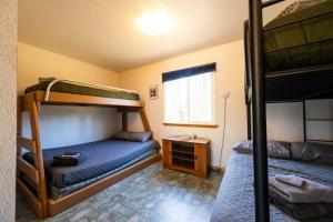 a bedroom with two bunk beds and a window at Grayling Getaway, Cabin 1 at Lower Kenai Lodge in Kenai