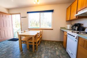 a kitchen with a wooden table and a table and chairs at Grayling Getaway, Cabin 1 at Lower Kenai Lodge in Kenai