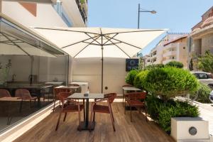 a table and chairs with an umbrella on a balcony at The City Hotel & Suites in Rethymno