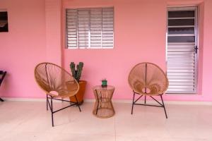 three chairs in a room with a pink wall at Chalé Rosa - Top Country Ranch in Boituva