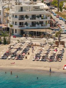 a beach with a large building and people in the water at The Palms Kos in Kos
