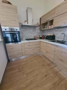 a kitchen with wooden cabinets and a wooden floor at Casa Antonella in Sìnnai