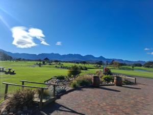 a park with benches and a green field with mountains at The Oak in Strand