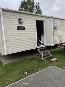 a large white trailer with a door open at Seawick Holiday Park in Jaywick Sands