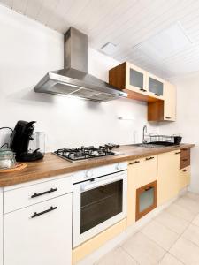 a kitchen with white cabinets and a stove top oven at Chalet Forestôchat in Tressé +10 photos