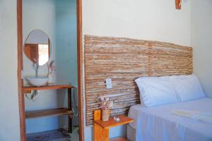 a bedroom with a bed and a mirror and a sink at Pousada vila jaguar - arpoador in Tutóia