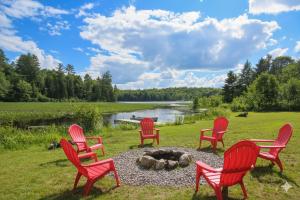 a group of red chairs sitting around a fire pit at Quiet Bay Lakeside Escape in Magnetawan