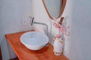 a bathroom with a white bowl and a vase on a wooden table at Pousada vila jaguar - arpoador in Tutóia