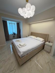 a bedroom with a large bed and a chandelier at Luma Apartment in Tecuci