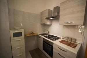a small kitchen with a stove and a sink at White Duomo Rooms in SantʼAgata di Militello +3 photos