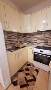 a kitchen with white cabinets and a sink and a stove at TI-NI Apartment in Gevgelija