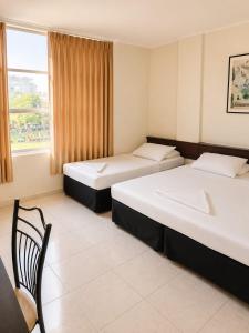 two beds in a room with a chair and a window at Off Day Inn in Male City