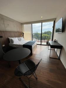 a bedroom with a bed and a table and a balcony at Lapso At Asís in Guadalajara