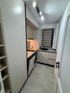 a small kitchen with white cabinets and a window at MOuntain View Apartment in Câmpulung +8 photos