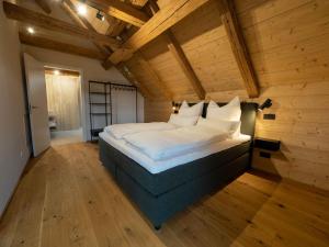 a large bed in a room with a wooden ceiling at Fuxbau Allgäu in Argenbühl