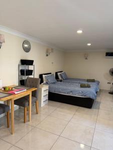 a bedroom with a bed and a table and a desk at Studio flat Gants Hill with Free Parking in Redbridge