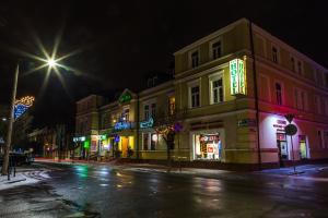 una calle de la ciudad por la noche con carteles de neón en Hotel Staromiejski, en Krasnystaw