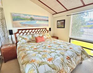 a bedroom with a bed with a floral bedspread and a window at Best Ocean and Mountain View! in Waikoloa Village