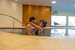 a man and a woman in a swimming pool at Hotel VillaReal Charme in Guaratuba