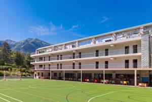 a hotel with a soccer field in front of it at Ostello Sport Center in Monte Ceneri