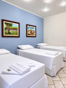four beds in a room with blue walls at Hotel Pousada Garoupas in São Sebastião