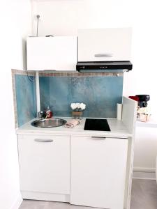 a white kitchen with a sink and a microwave at Cocon doré au coeur de Limay in Limay