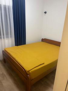 a yellow bed in a room with blue curtains at Guest House Vuthaj in Vusanje