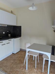 a kitchen with a white table and two chairs at Studio Issoire pour 2 adultes et 1 enfant in Issoire