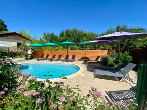a swimming pool with chairs and umbrellas at Domaine Ô Clair de Lune - Chambres d'Hôtes et Gîtes à Sarlat - Accès Cité Médiévale 5 minutes à pied - Parking - SPA & Massages en option - Piscine de saison in Sarlat-la-Canéda