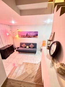 a living room with a couch and a clock on a wall at Habitaciones cómodas en Coto Galeana Guadalajara in Guadalajara